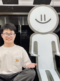 a man sitting in front of a statue of a smiling man